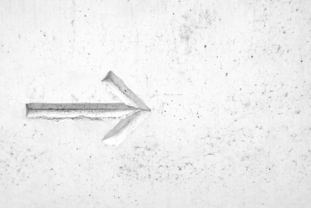 an arrow engraved on a white plaster wall